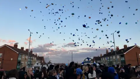 Sam Read/BBC Balloons flying between two lampposts above a crowd of people