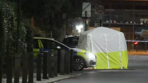 PA Media A police car and tent on Battersea Church Road