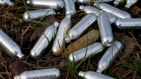 PA Media Laughing gas cannisters lie in the grass
