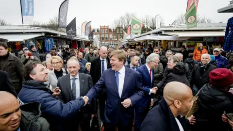 Getty Images Dutch King Willem-Alexander (C) shakes hands at the Haagse Markt during his surprise visit in the Transvaalkwartier and Schilderswijk districts in The Hague on 23 March 2016.