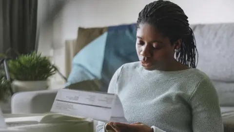 Getty Images Young woman reading energy bill