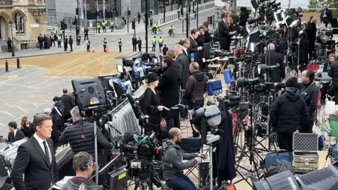 General view of assembled ranks of members of the world's broadcasting media opposite Westminster Abbey