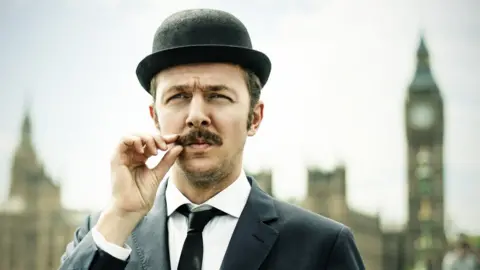 Getty Images A man in a bowler hat twiddles his moustache
