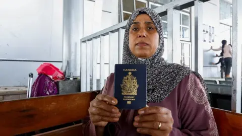 Reuters Palestinian-Canadian Seham al-Batnejy displays her passport as she waits at Rafah border crossing after evacuations were suspended following an Israeli strike on an ambulance, in Rafah in the southern Gaza Strip