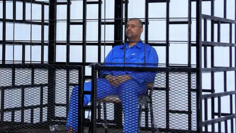 Reuters Saif al-Islam Gaddafi, son of late Libyan leader Muammar Gaddafi, attends a hearing behind bars in a courtroom in Zintan, 25 May 2014