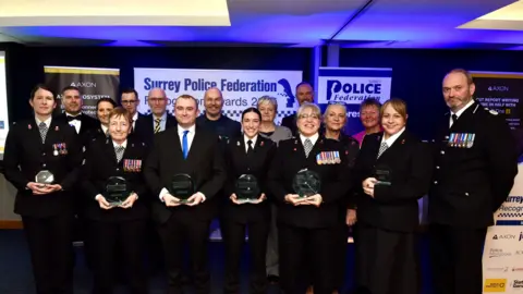 Surrey Police Federation A group of police officers in ceremonial uniform. There are women and men across a range of ages. 