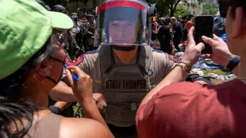 Getty Images Pro-Palestinian protesters confront a Texas State trooper at the University of Texas at Austin