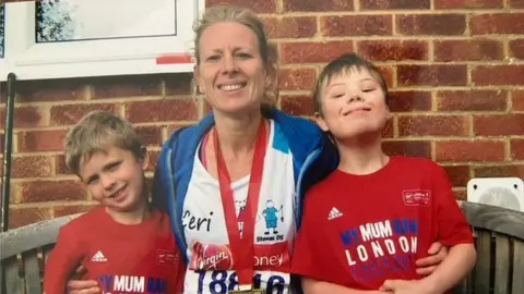 Family photo Lloyd, Ceri and another boy together. Ceri is wearing her London marathon finisher's medal