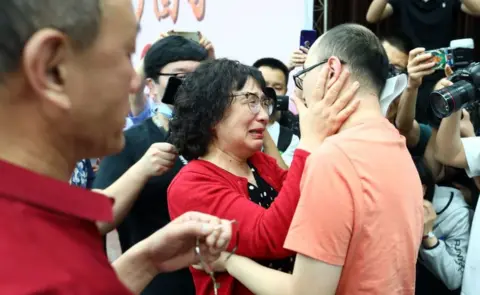 Getty Images Li Jingzhi and her son embrace for the first time in 32 years