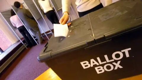 BBC Woman posting her paper into ballot box at polling station