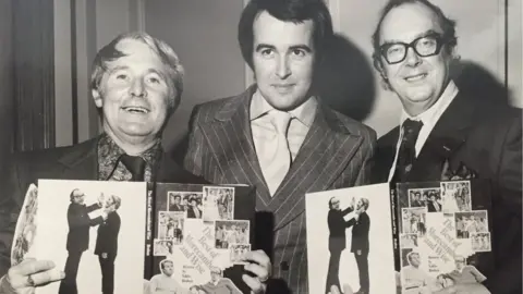 Colin Webb Ernie Wise, Colin Webb and Eric Morecambe holding copies of a book they were all involved in creating