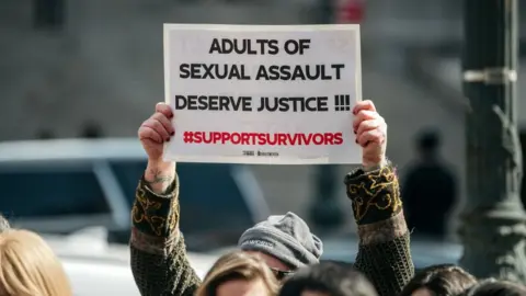 Getty Images A demonstrator holds a sign overhead at a rally in support of the Adult Survivors Act on February 28, 2020 in New York City.