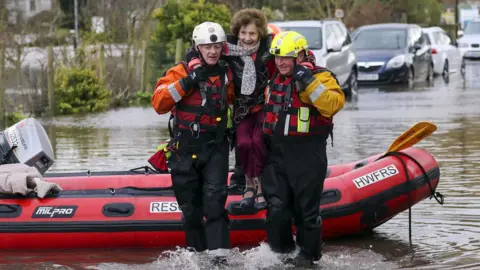 PA Media Rescue workers lifted a woman to safety in the village of Whitchurch