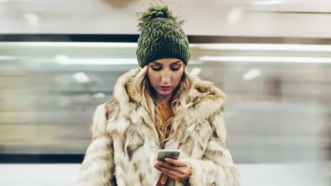 Getty Images A woman looks at her phone