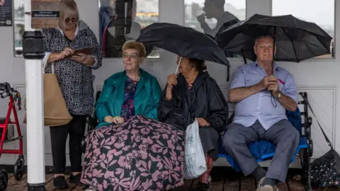 Getty Images Daytrippers shelter from a downpour at Brighton Pier on Wednesday