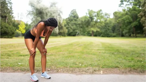 Martin Novak/Getty Woman taking a breather after running in a park