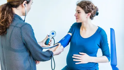 Science Photo Library Doctor takes pregnant woman's blood pressure