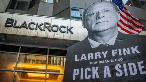 Getty Images articipant seen holding a sign at the protest. More than 100 New Yorkers on the frontlines of the climate crisis, including faith leaders and youth, held a protest outside BlackRock Headquarters in Manhattan, where their annual shareholders meeting took place.