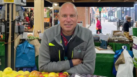 Hollie Cole/BBC Stephen Wetherill a market trader by his stall in Peterborough