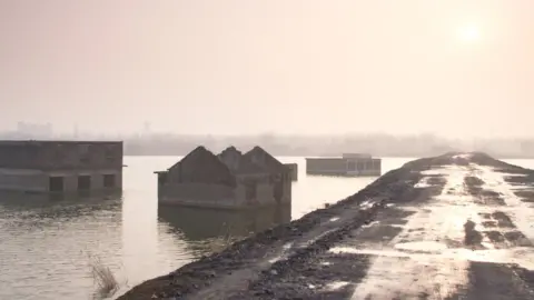 Half submerged, derelict houses on a man-made lake in Anhui