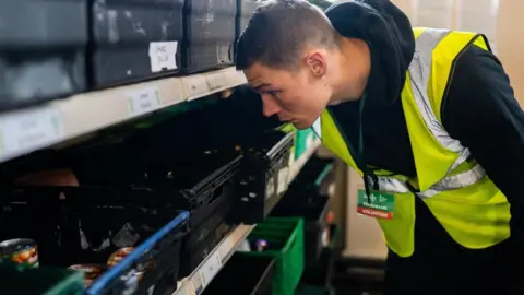 Bournemouth Foodbank Chris Billam-Smith wearing a hi-vis vest and sorting food at Bournemouth Foodbank warehouse