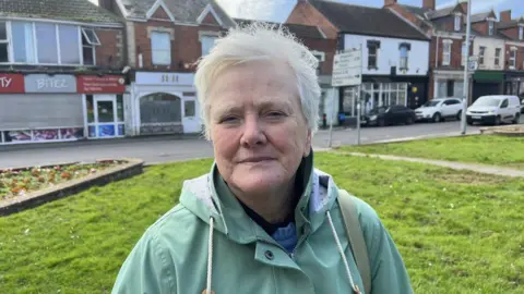 Women stood looking at the camera wearing a green coat