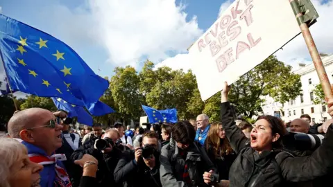 Reuters A crowd faces off, with EU and UK flags visible, while an anti-Brexit campaigner waves as sign demanding Brexit be stopped