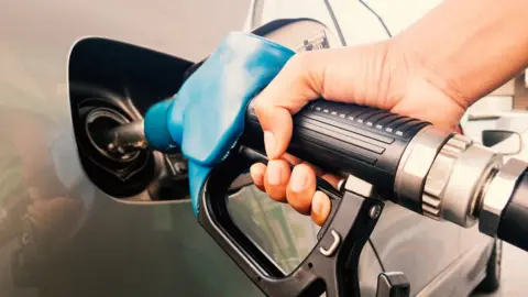 Getty Images Petrol pump nozzle going into a car