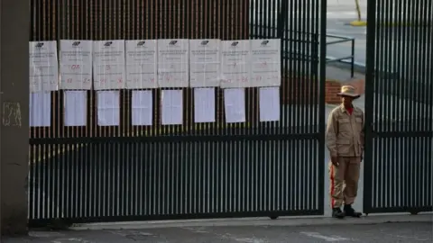 AFP A Bolivarian militia stands guard at the gate of a school in Caracas after polling stations closed on election day in Venezuela, on May 20, 2018.