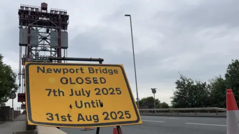 A sign reading Newport Bridge closed 7th July 2025 until 31 August 2025 can be seen with traffic cones in front of the large bridge.