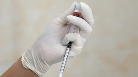 Reuters Latex gloved hand using syringe.