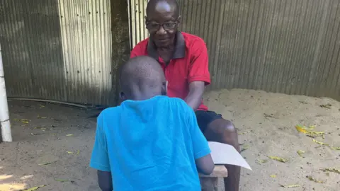 Hassan Lali/BBC A man talking to a young person who has their back to the camera