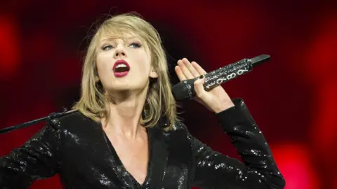 Getty Images Taylor Swift holds microphone on-stage while performing