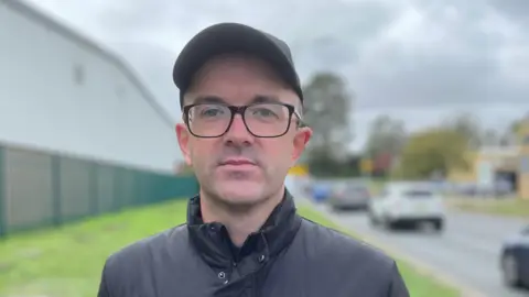 Shaun Whitmore/BBC Russell Bradnam, standing by the side of the road in Newmarket