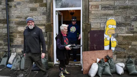 Getty Images People begin the clean-up following yesterday's flooding in Newcastleton, Scotland.