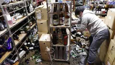 Reuters Store owner cleaning up smashed bottles in Fukushima liquor shop