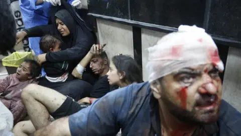 Anadolu Casualties are treated while sitting on the floor at Al-Aqsa Martyrs Hospital in Deir al-Balah, in central Gaza (11 December 2023)