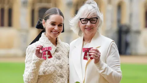 Emilia and Jenny Clarke hold their MBEs outside Windsor Castle