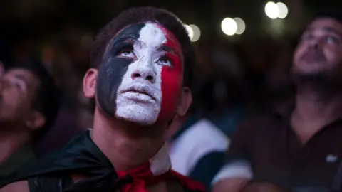 EPA Egyptian men watch their natiional team play Congo Brazzaville on a big TV screen