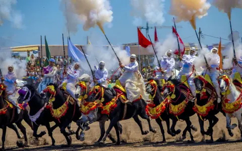 Abu Adem Muhammed/Getty Images Traditional horse riders firing guns in a Tbourida in Bouznika, Morocco - Wednesday 10 May 2023