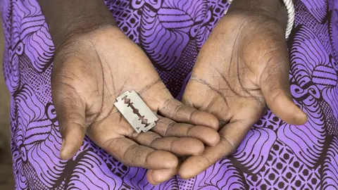 A woman holds a razor blade in Burkina Faso