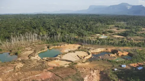 Getty Images Forest destruction caused by mining gold deposits. Soil is blasted with powerful jets of water, causing chemical pollution which has a major impact on the rain forest environment, Venezuela, South America - stock photo