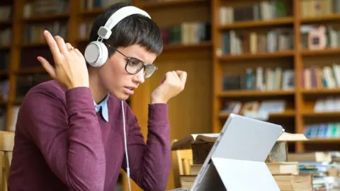 Getty Images stock image of an annoyed woman wearing headphones