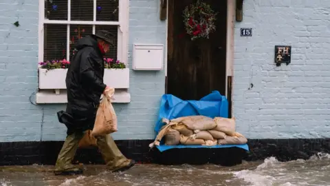 PA Media A person places sand bags outside a property in Langstone, Hampshire