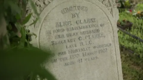 The gravestone for Sergeant Clarke, worn down from time, with a dedication from his wife Alice Clarke