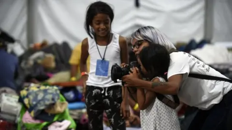 AFP A photographer shows a young migrant girl how to use her camera