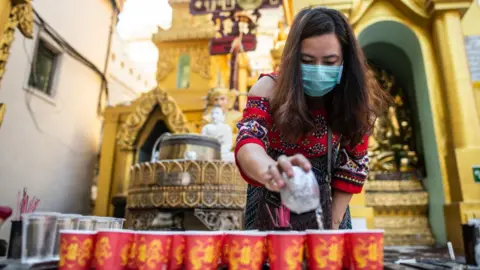 Getty Images A woman wearing face mask, as she visits Shwedagon pagoda in Yangon