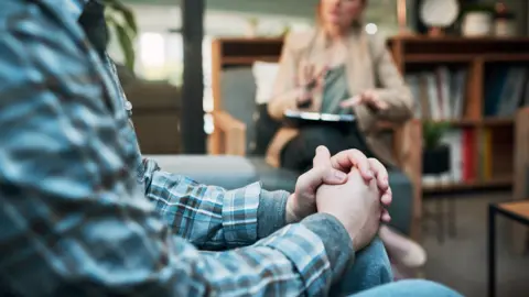 Getty Images View of clasped hands with a blurred figure in the background.