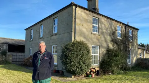 Martin Beal in front of his home