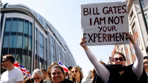 Getty Images Woman holds sign about Bill gates at protest